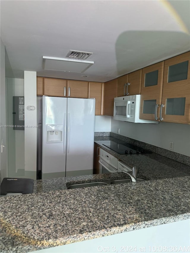 kitchen featuring kitchen peninsula, stone counters, and white appliances