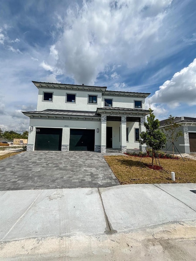 view of front of home with a garage, stucco siding, stone siding, and decorative driveway