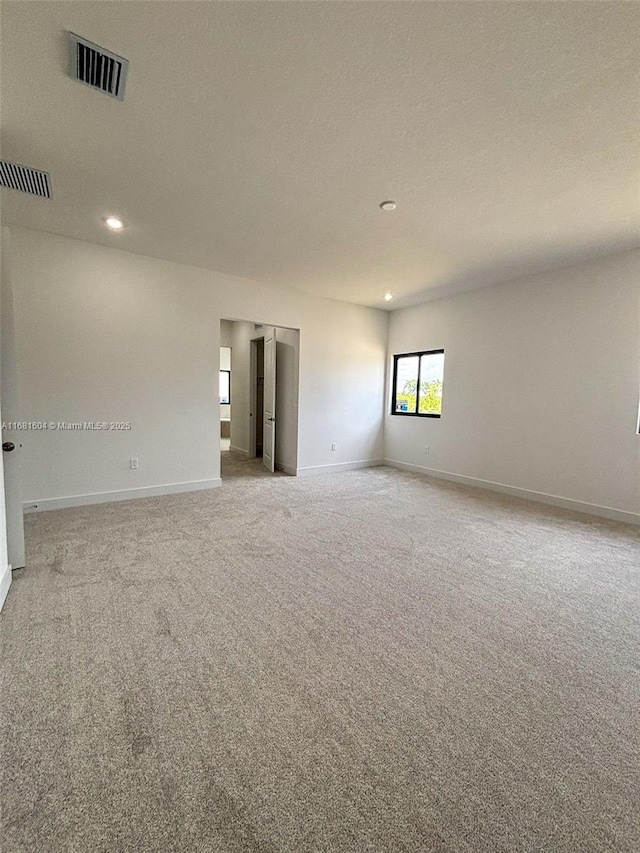 carpeted empty room featuring recessed lighting, visible vents, and baseboards