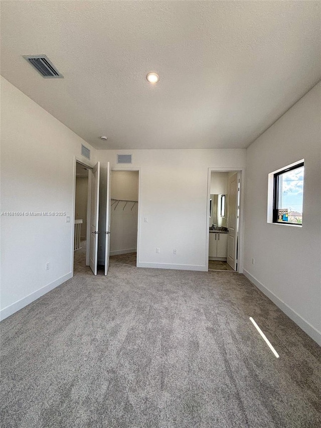 unfurnished bedroom featuring carpet flooring, visible vents, a textured ceiling, and baseboards