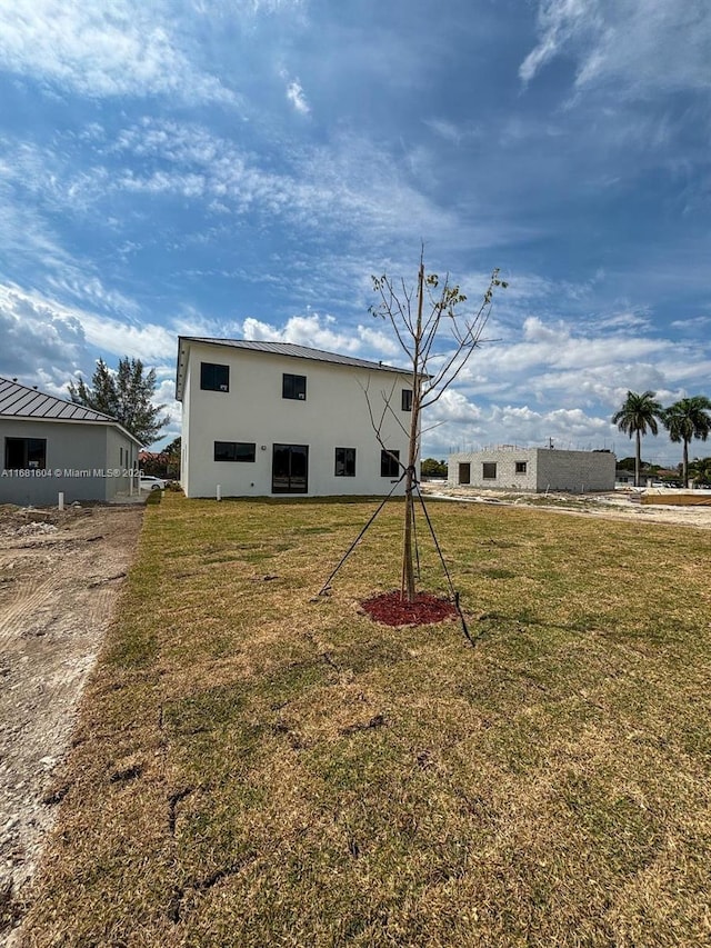 back of property with a yard and stucco siding