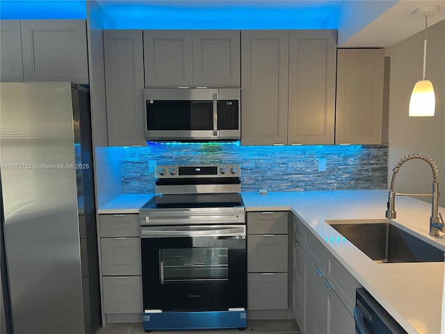 kitchen featuring pendant lighting, appliances with stainless steel finishes, gray cabinets, and sink