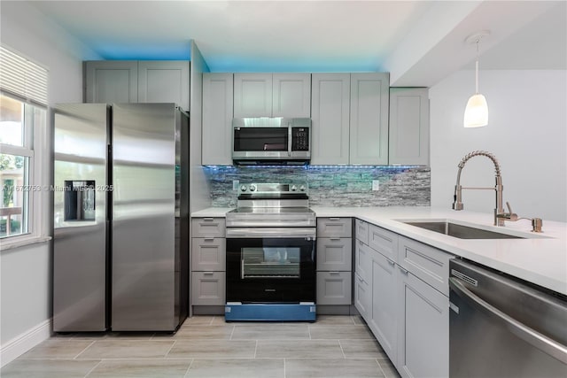 kitchen with hanging light fixtures, appliances with stainless steel finishes, sink, and gray cabinetry