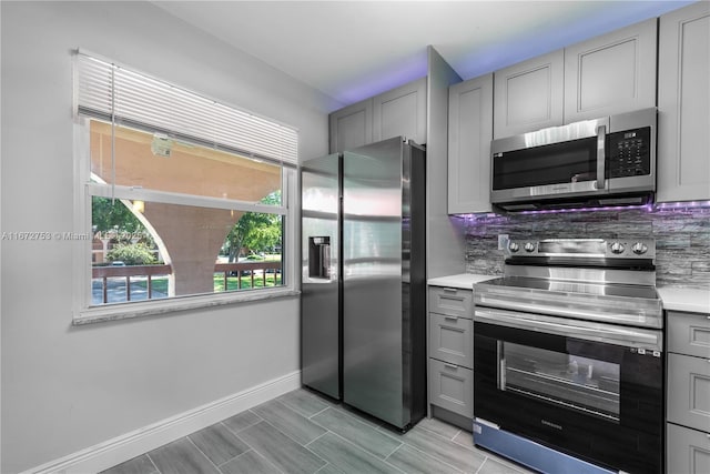 kitchen featuring backsplash, appliances with stainless steel finishes, and gray cabinets