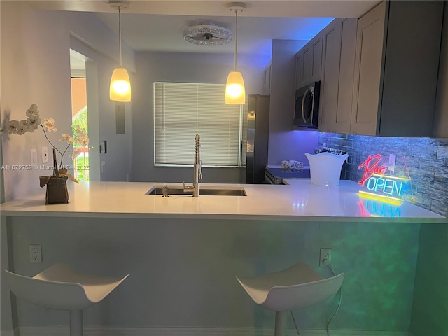 kitchen featuring sink, pendant lighting, appliances with stainless steel finishes, and kitchen peninsula