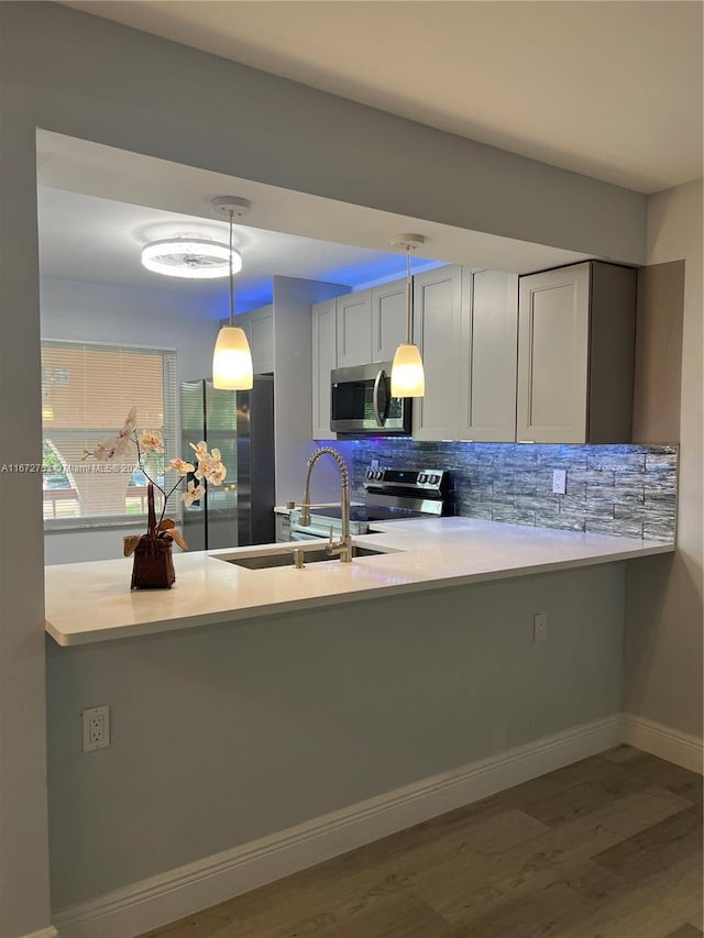 kitchen featuring decorative light fixtures, kitchen peninsula, backsplash, and stainless steel appliances