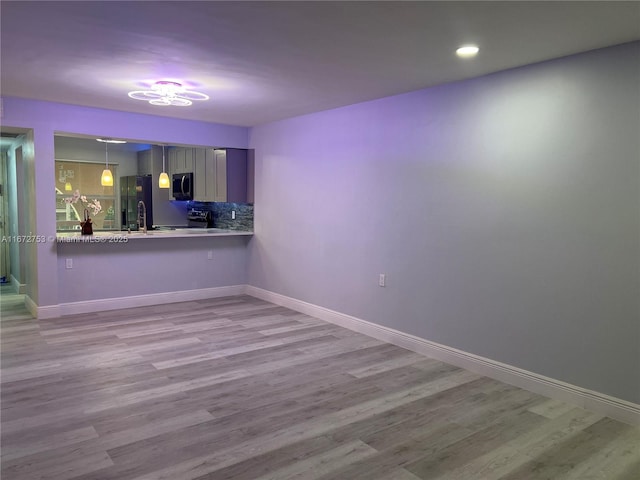 bar featuring light wood-type flooring, refrigerator with ice dispenser, tasteful backsplash, and hanging light fixtures