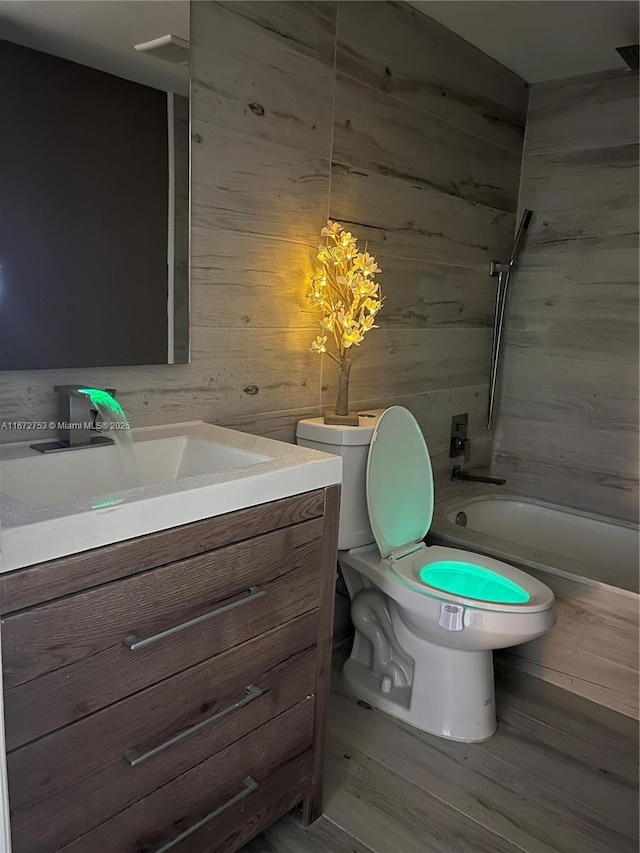 bathroom with hardwood / wood-style floors, toilet, vanity, and wood walls