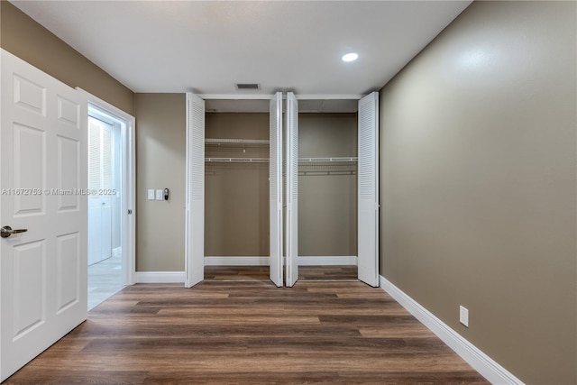 unfurnished bedroom with dark wood-type flooring and two closets