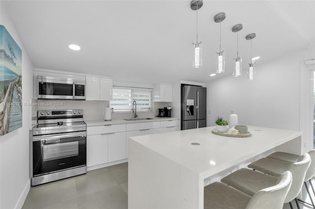 kitchen with a kitchen island, appliances with stainless steel finishes, hanging light fixtures, and white cabinetry