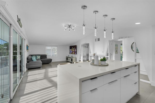 kitchen featuring a kitchen island, hanging light fixtures, vaulted ceiling, an inviting chandelier, and white cabinets