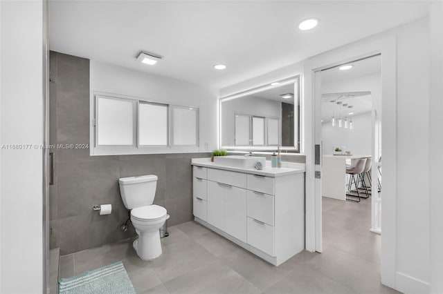 bathroom featuring vanity, toilet, tile walls, and tile patterned flooring