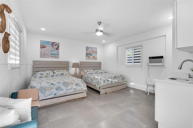 bedroom featuring a wall unit AC, sink, and ceiling fan