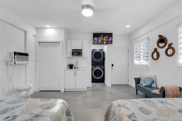 bedroom with a wall mounted AC, ceiling fan, stacked washer / drying machine, a closet, and sink