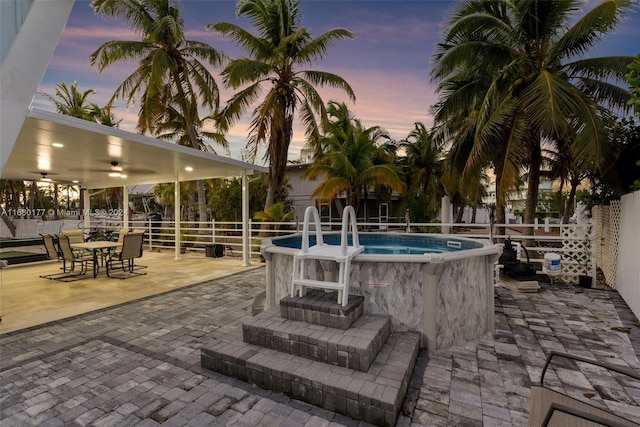 pool at dusk featuring a patio