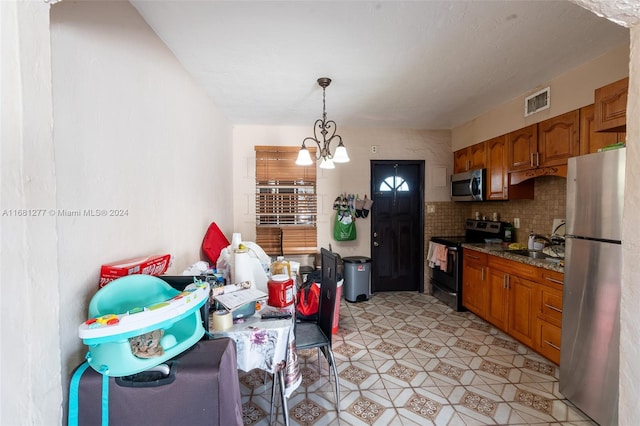 kitchen featuring appliances with stainless steel finishes, sink, backsplash, decorative light fixtures, and an inviting chandelier