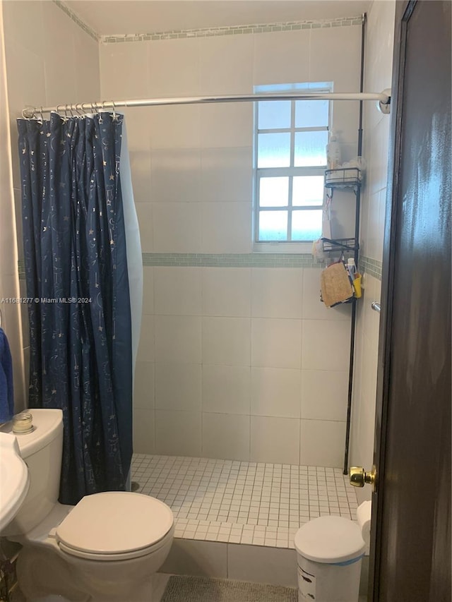 bathroom with toilet, tile patterned floors, a shower with curtain, and tile walls