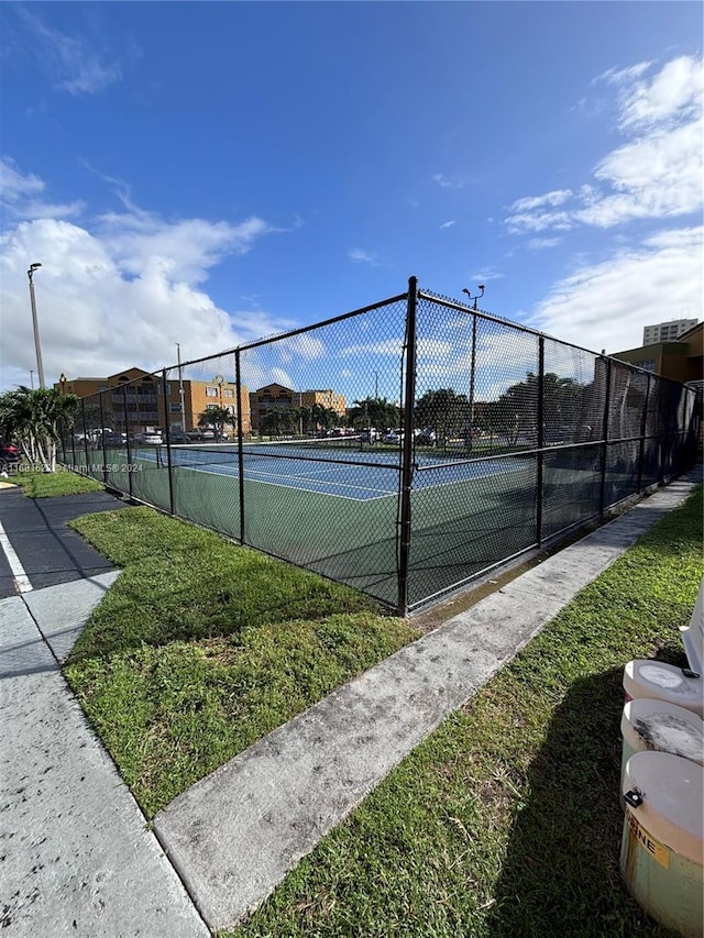 view of tennis court featuring a yard