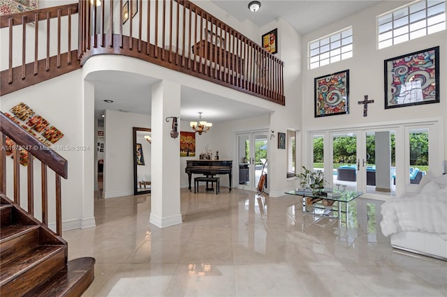 living room featuring a towering ceiling, french doors, and an inviting chandelier