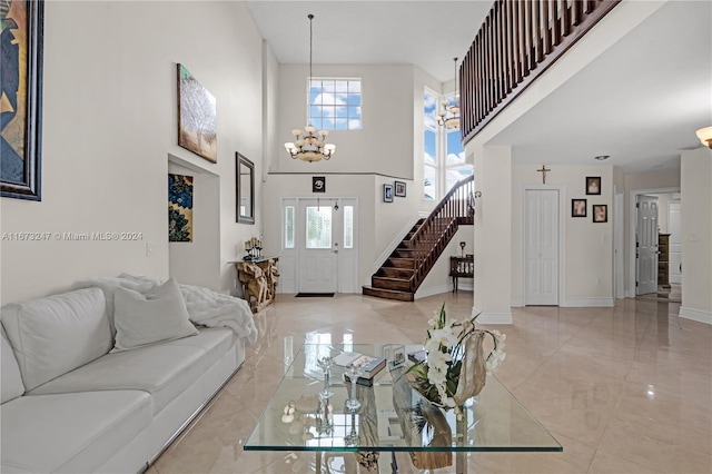 living room with a towering ceiling, an inviting chandelier, and a healthy amount of sunlight