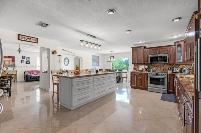 kitchen with backsplash, a breakfast bar, a center island, pendant lighting, and appliances with stainless steel finishes