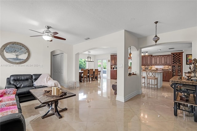 living room featuring a textured ceiling and ceiling fan with notable chandelier