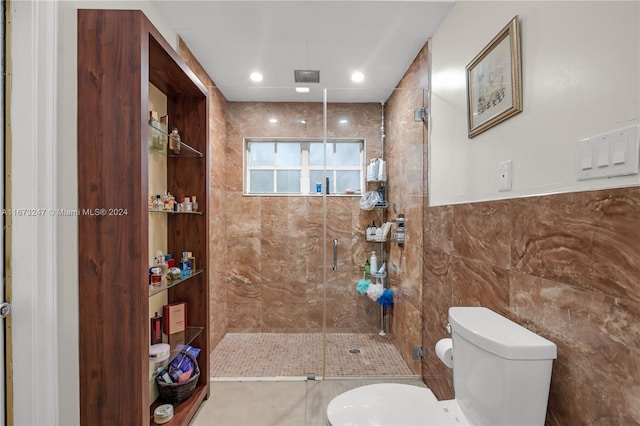 bathroom with toilet, an enclosed shower, tile patterned floors, and tile walls