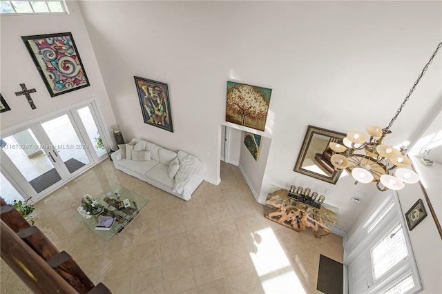 living room featuring a towering ceiling, french doors, a chandelier, and light tile patterned flooring