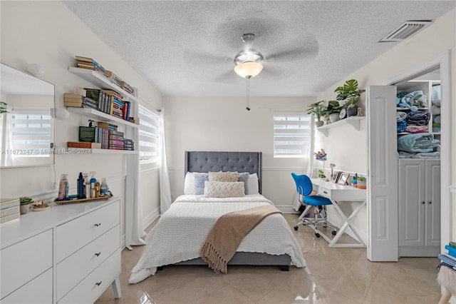 tiled bedroom with a textured ceiling and ceiling fan