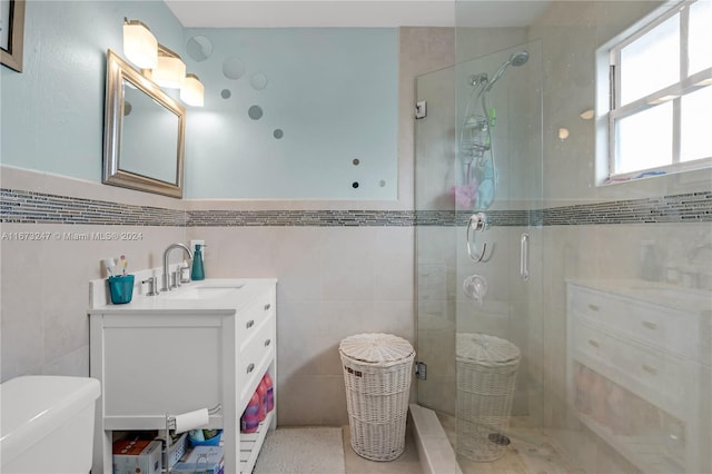 bathroom featuring vanity, toilet, tile walls, and a shower with door