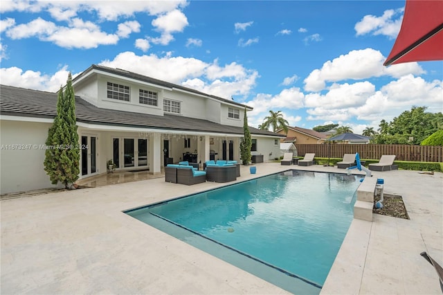 view of pool with french doors, an outdoor living space, and a patio