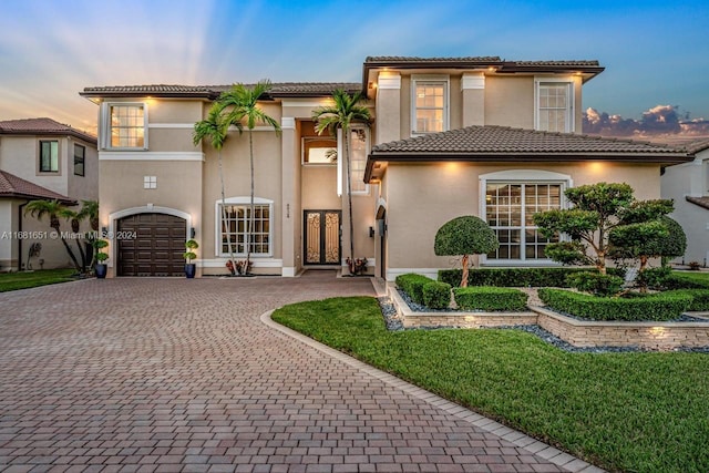 mediterranean / spanish-style home featuring a yard and a garage