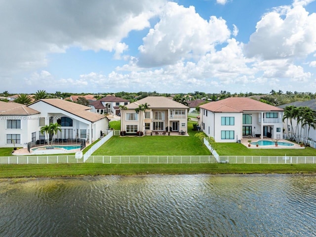 back of property featuring a yard, a patio, a water view, and a fenced in pool