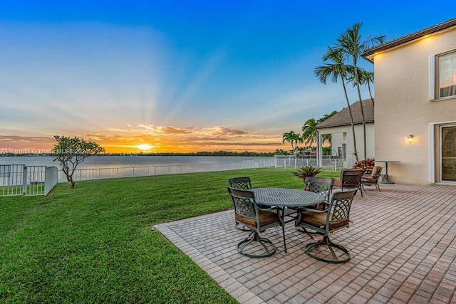 yard at dusk featuring a patio and a water view