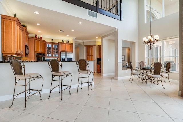 kitchen featuring kitchen peninsula, dark stone counters, crown molding, a notable chandelier, and appliances with stainless steel finishes