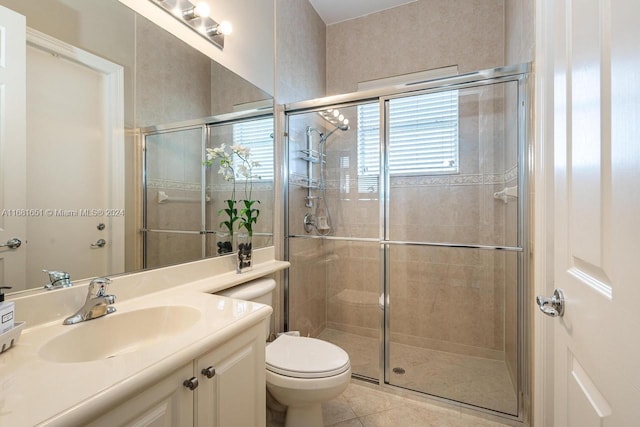 bathroom featuring vanity, tile patterned flooring, toilet, and an enclosed shower