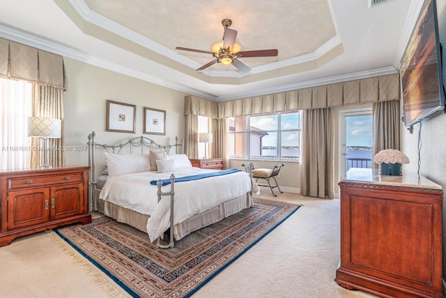 bedroom featuring ceiling fan, crown molding, a tray ceiling, and light colored carpet