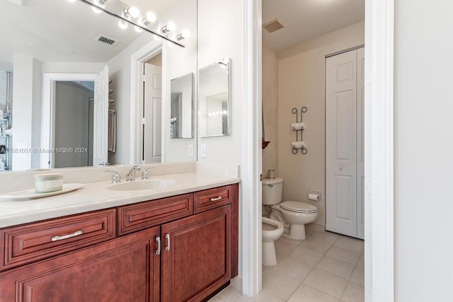 bathroom featuring vanity, toilet, tile patterned floors, and a bidet