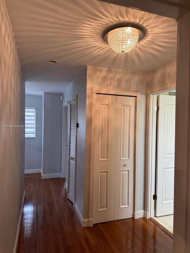 hall featuring dark wood-type flooring and an inviting chandelier