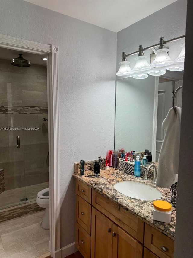 bathroom with vanity, toilet, and a shower with door