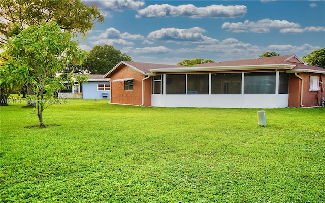 back of property with a lawn and a sunroom