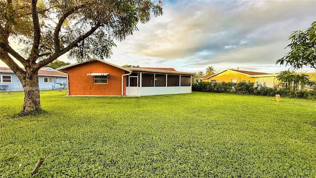 rear view of house with a yard and a sunroom