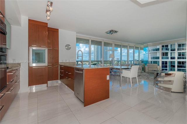 kitchen with light stone countertops, a wall of windows, light tile patterned floors, and stainless steel appliances