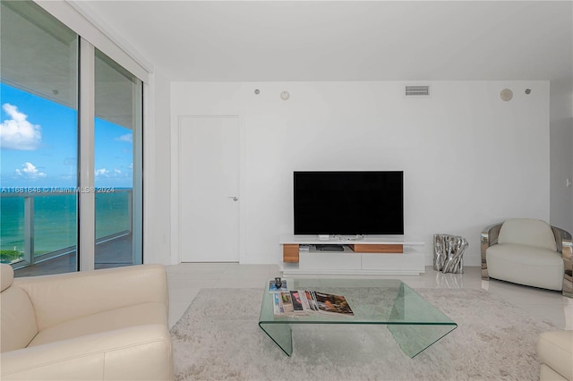 living room with a wealth of natural light, a water view, and light tile patterned flooring