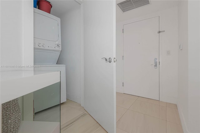 laundry room featuring stacked washer and dryer and light tile patterned flooring