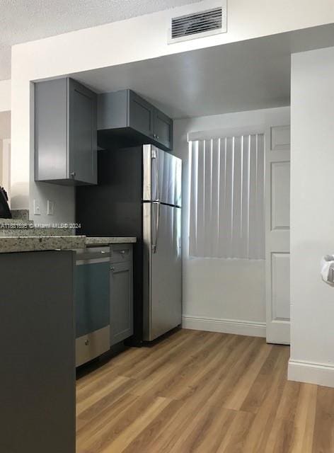 kitchen featuring light hardwood / wood-style flooring, dark stone countertops, stainless steel appliances, and gray cabinetry