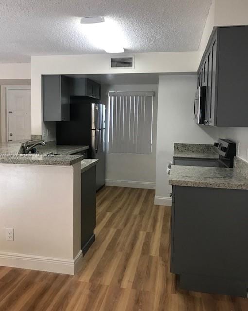 kitchen featuring gray cabinetry, stone countertops, electric range, dark hardwood / wood-style flooring, and kitchen peninsula