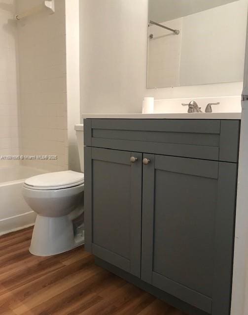 full bathroom with wood-type flooring, toilet, shower / washtub combination, and vanity