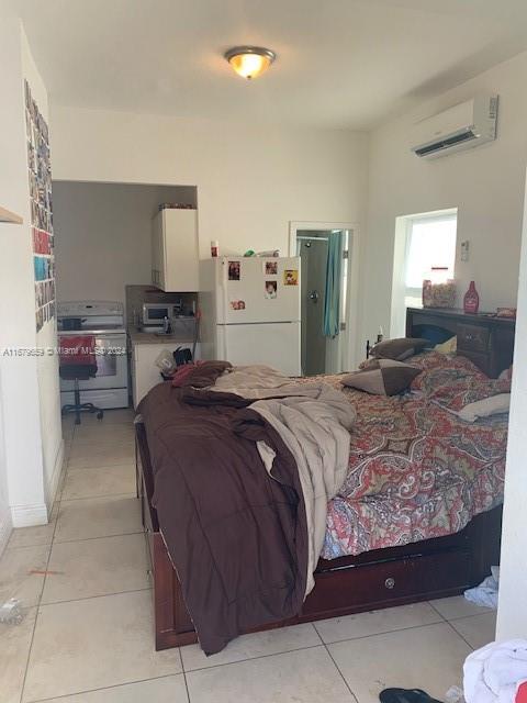 tiled bedroom with a wall mounted AC and white refrigerator