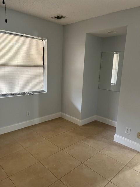 empty room with a textured ceiling and light tile patterned flooring